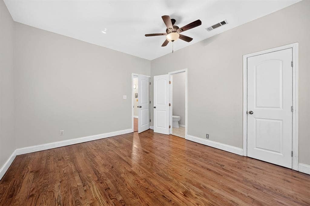 Room featuring wood-finish flooring, a central ceiling fan with an integrated light fixture, and two-panel interior doors