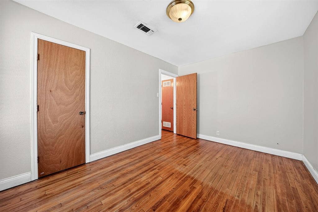 Room featuring wood-finish flooring, neutral-toned walls, and wood-finish doors