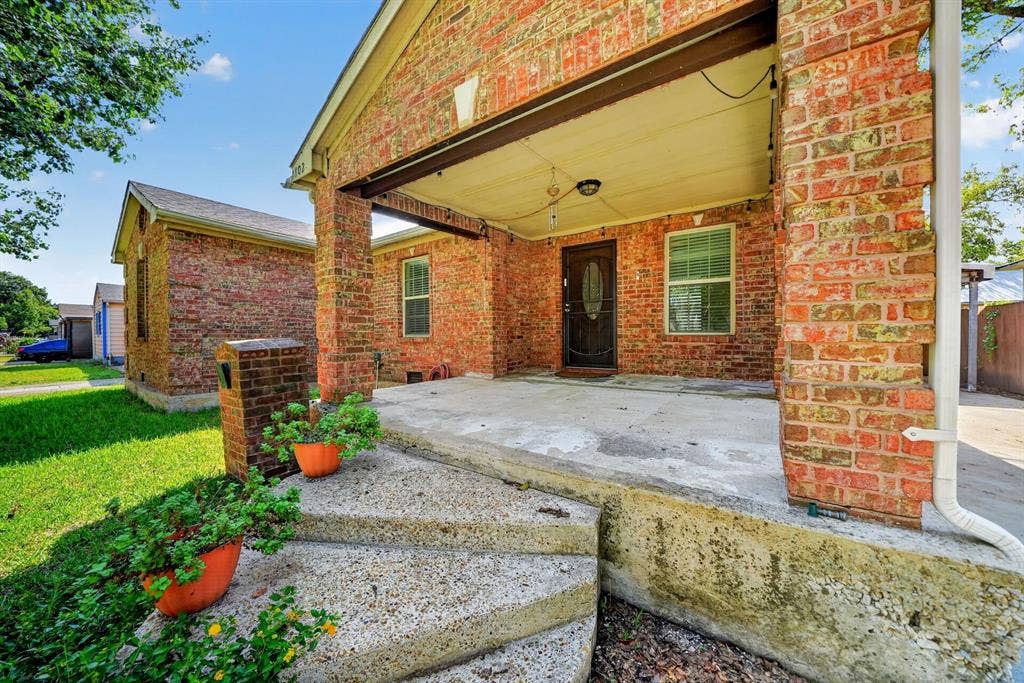 Brick exterior featuring a covered front porch, concrete curved steps, a solid masonry mailbox, and a paneled entry door with an oval glass inset