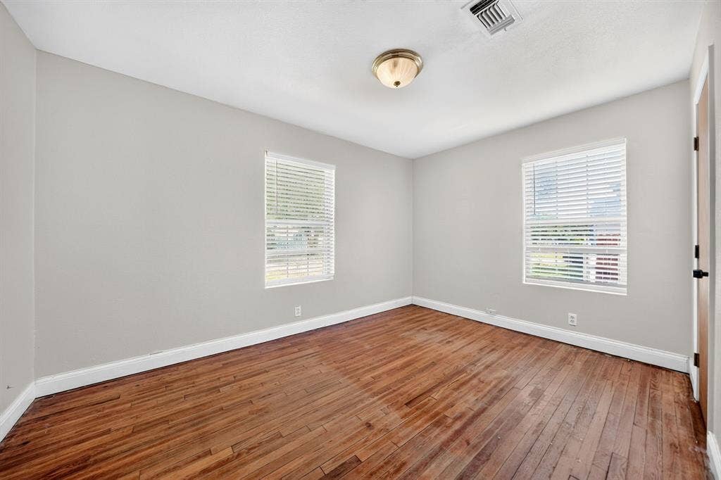 Interior space featuring wood-finish flooring, two dual-pane windows with horizontal blinds, and a neutral wall finish