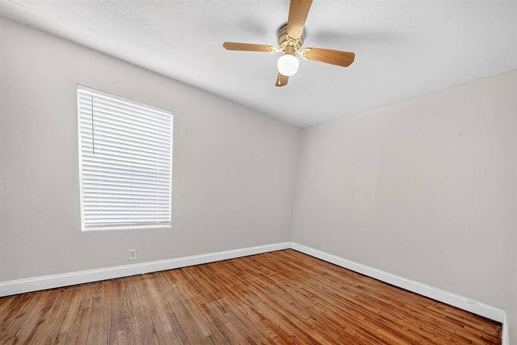 Interior room featuring wood-finish flooring, neutral wall paint, and a ceiling-mounted fan with integrated light fixture