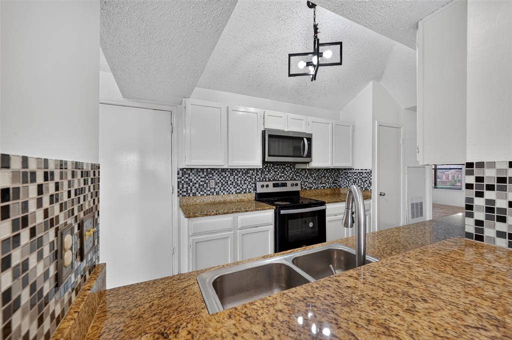 583 Kirkland Drive, Coppell, TX 75019 Granite countertops, stainless steel sink with gooseneck faucet, full suite of stainless steel appliances, white cabinetry, and multi-tone mosaic tile backsplash