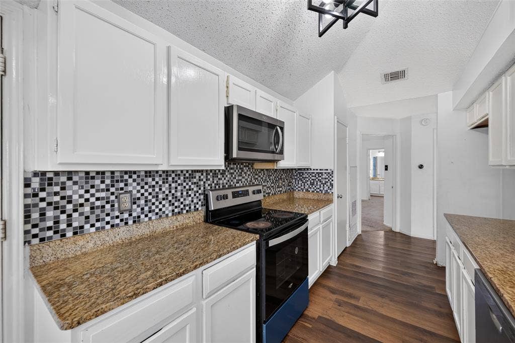 583 Kirkland Drive, Coppell, TX 75019 White cabinetry with matte black hardware, mosaic tile backsplash, granite-style countertops, stainless steel appliances, and wood-finish flooring