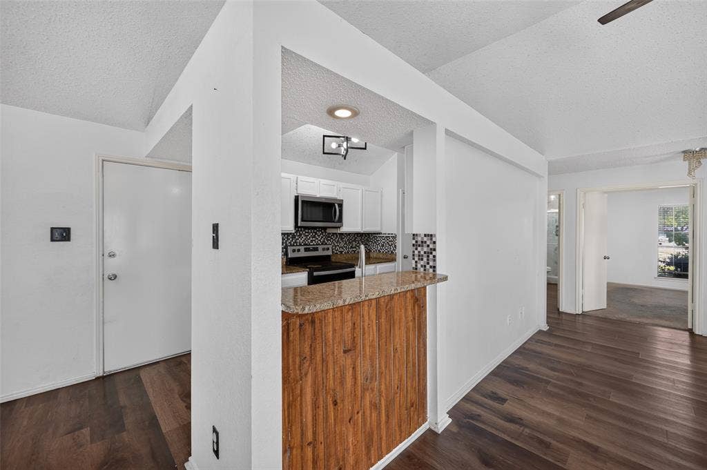 583 Kirkland Drive, Coppell, TX 75019 Wood-finish flooring throughout, with a breakfast bar featuring a stone-look countertop and wood-paneled base