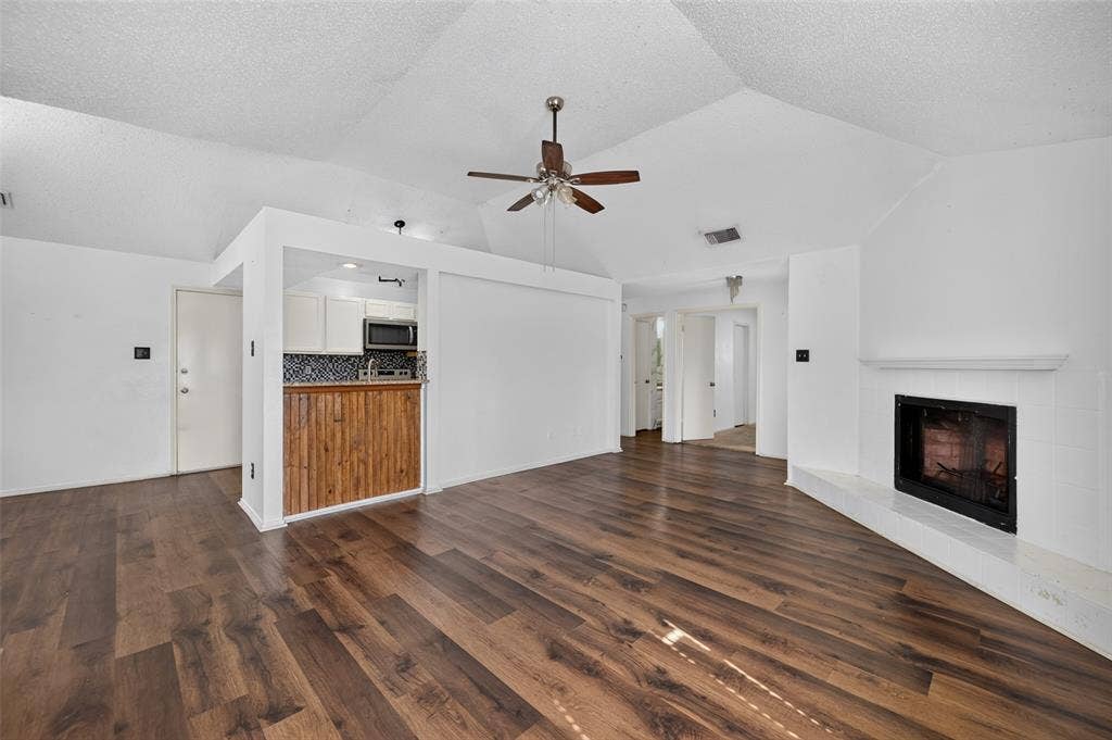 583 Kirkland Drive, Coppell, TX 75019 Wood-finish flooring, vaulted ceiling, built-in fireplace, ceiling fan, and a kitchen pass-through with wood-paneled detailing