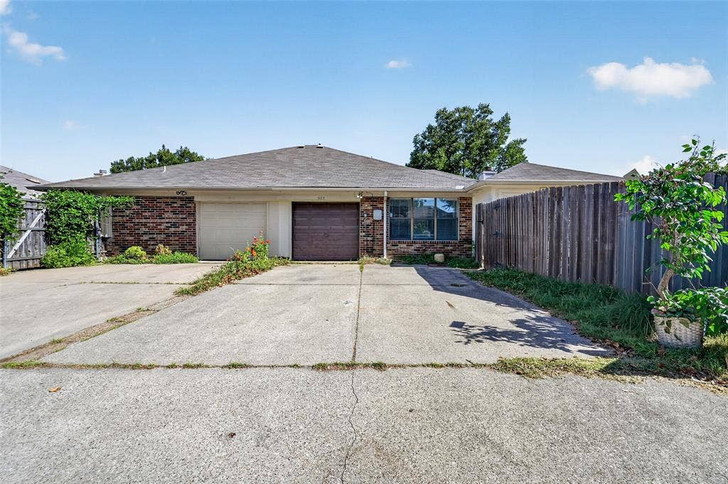 583 Kirkland Drive, Coppell, TX 75019 Brick facade residence with an attached garage, pitched roof, and a privacy fence