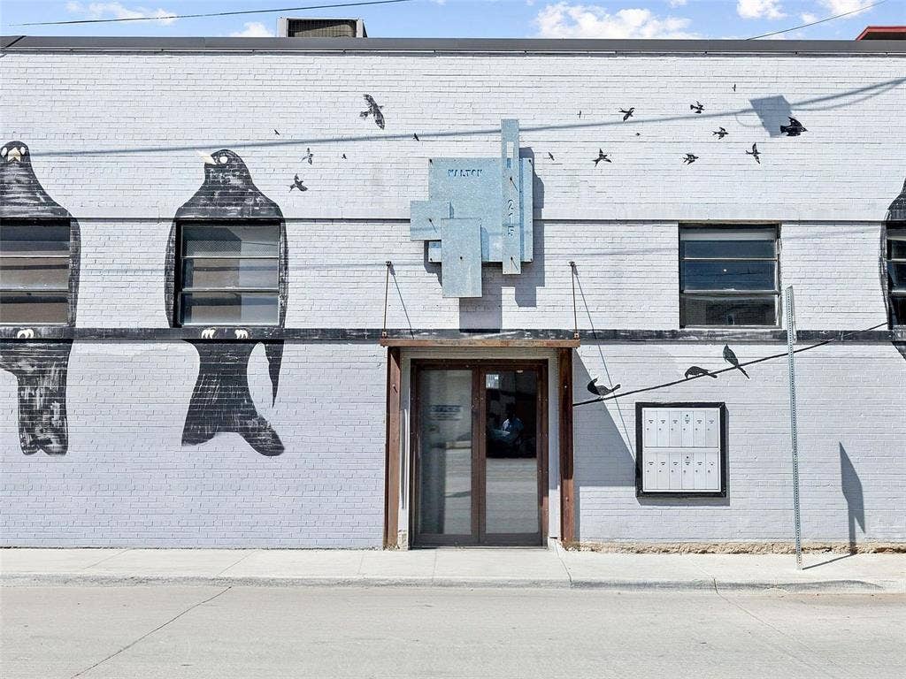 215 N Walton Street, #2, Dallas, TX 75226 Painted masonry exterior featuring mural artwork, metal-frame glass entry door, multi-pane industrial-style windows, and mounted metal mail distribution station