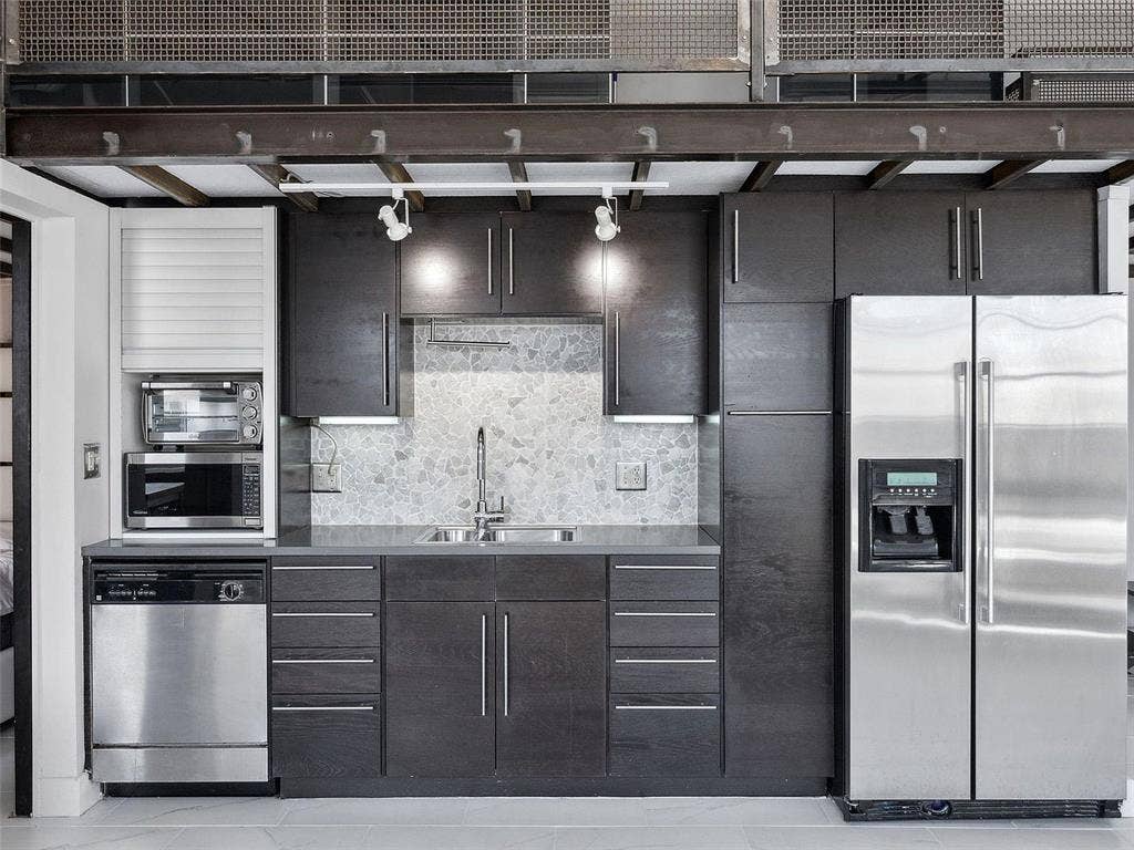 215 N Walton Street, #2, Dallas, TX 75226 Kitchen featuring dark wood cabinetry, stainless steel appliances, mosaic tile backsplash, solid-surface countertops, and industrial-style exposed steel ceiling beams
