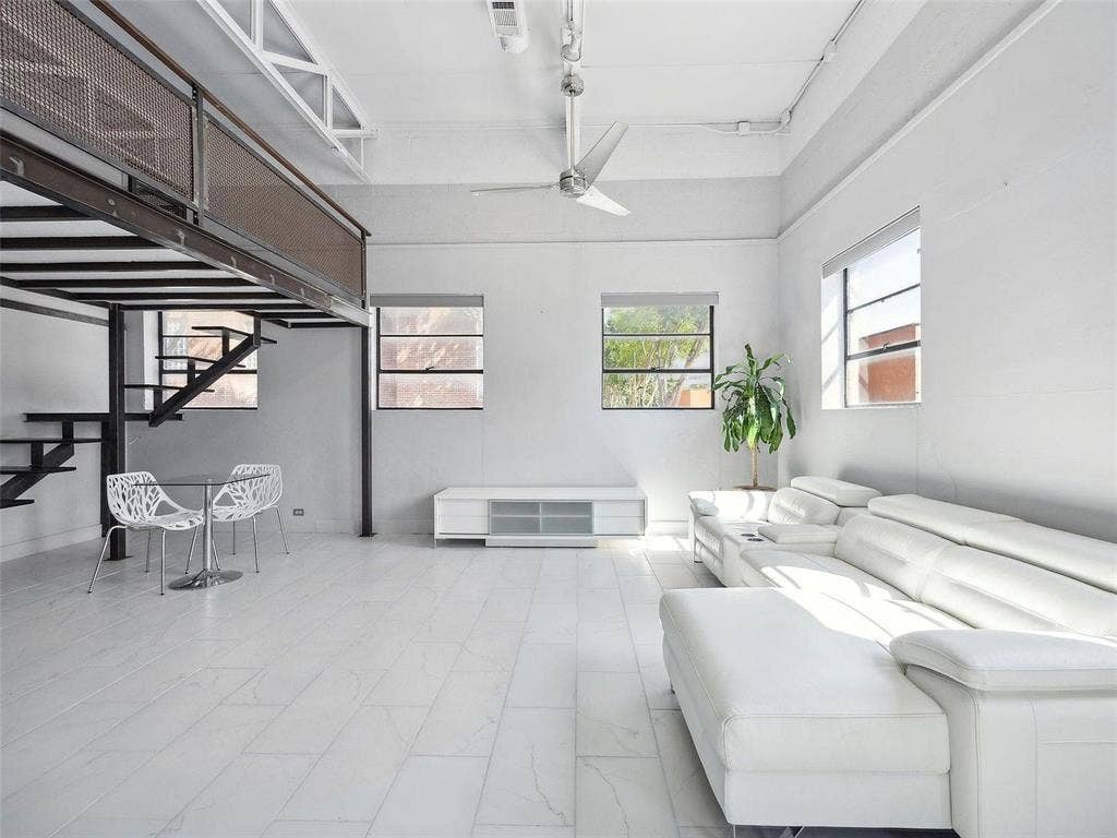 215 N Walton Street, #2, Dallas, TX 75226 Industrial-style interior featuring high ceilings with exposed structural elements, a metal mezzanine with mesh railing, large windows, and neutral tile flooring