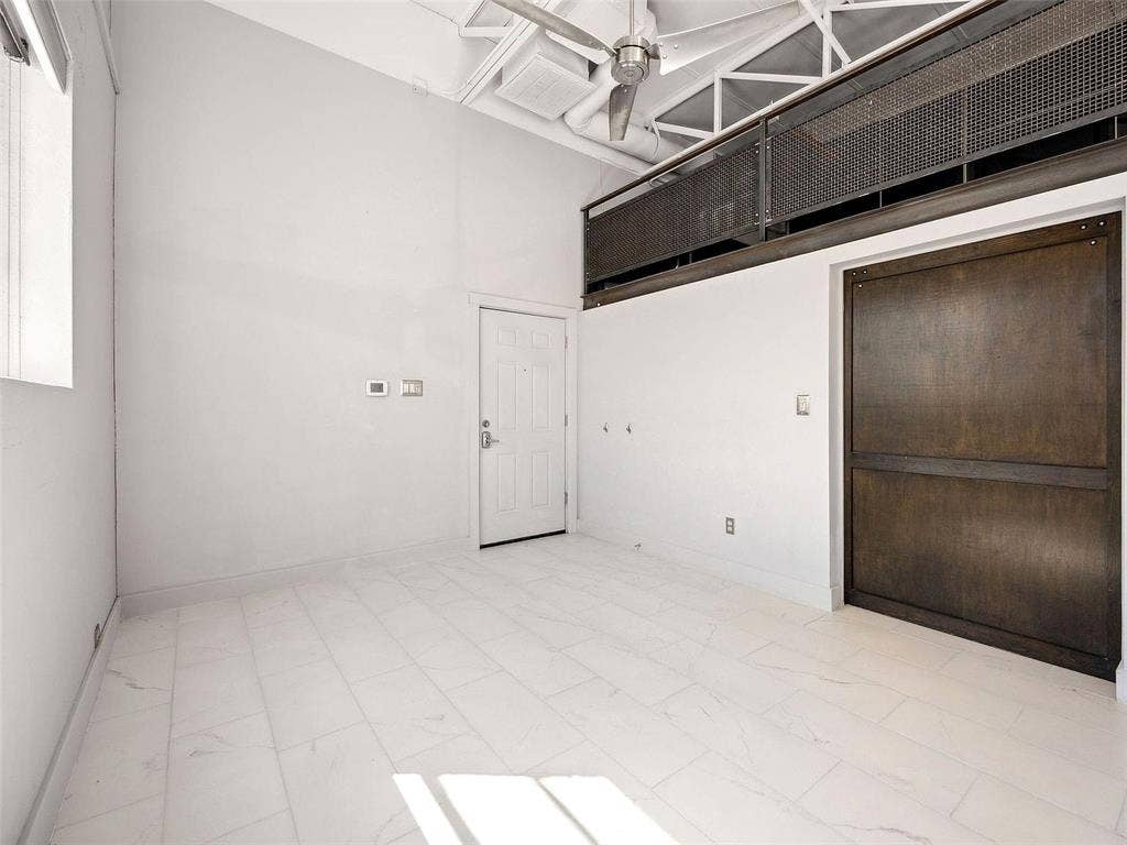 215 N Walton Street, #2, Dallas, TX 75226 High ceilings featuring exposed industrial-style trusses and a ceiling fan, large dark-finish sliding door, and neutral tile flooring