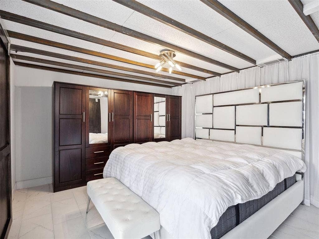 215 N Walton Street, #2, Dallas, TX 75226 Primary bedroom suite featuring exposed beam ceiling with recessed lighting, dark wood built-in cabinetry and wardrobe system, and a geometric accent wall with white paneling