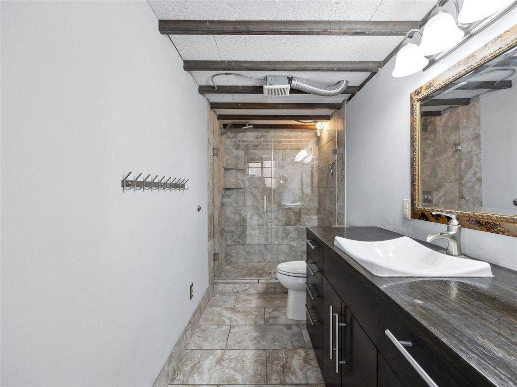 215 N Walton Street, #2, Dallas, TX 75226 Bathroom featuring an integrated vanity with a rectangular vessel sink, stone-surface countertop, exposed ceiling beams, and a walk-in shower with tile surround and glass enclosure