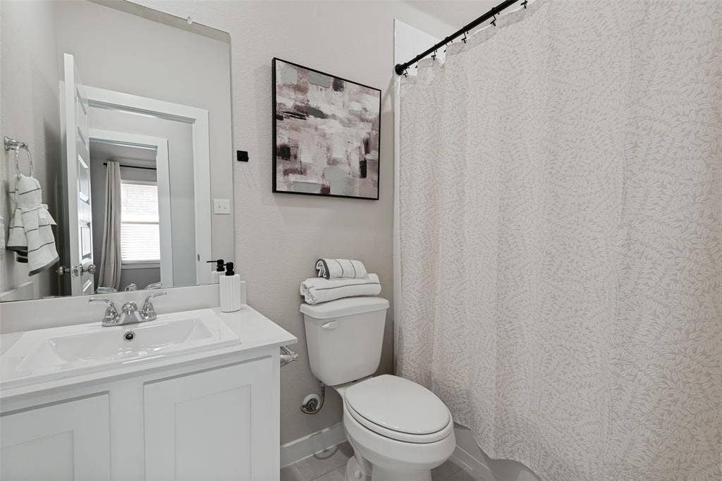 2808 Spring Side Drive, Royse City, TX 75189 Bathroom featuring a white vanity cabinet with a rectangular basin, chrome dual-handle faucet, integrated countertop, and an expansive wall-mounted mirror
