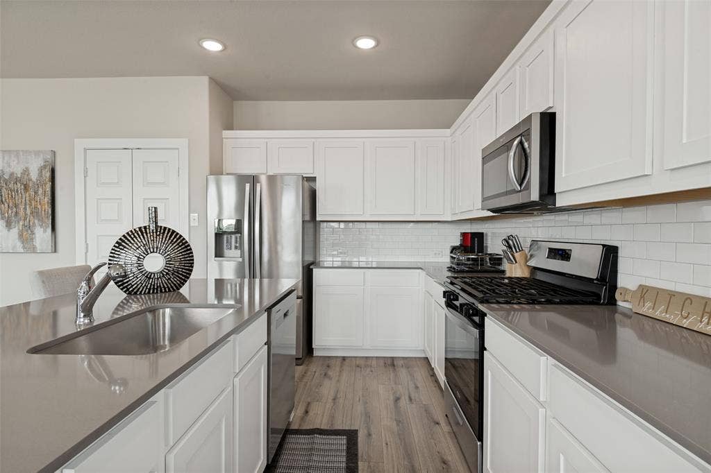 2808 Spring Side Drive, Royse City, TX 75189 Kitchen featuring white Shaker-style cabinetry, quartz countertops, a white subway tile backsplash, stainless steel appliances, and wood-finish flooring