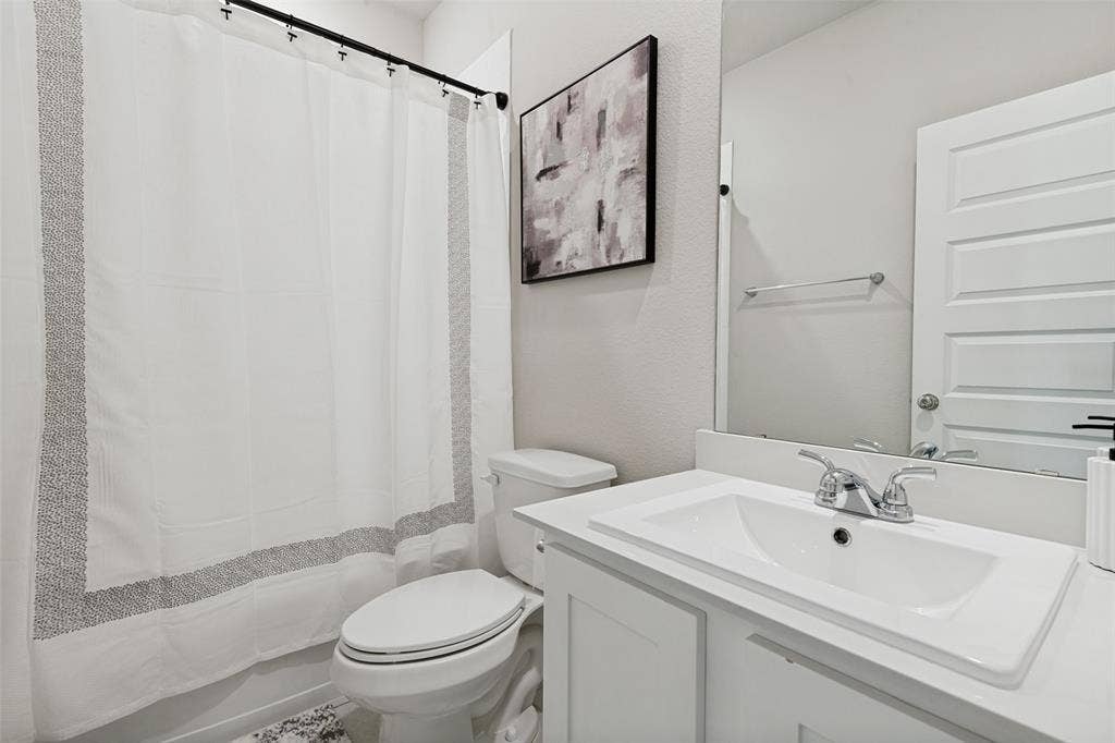 2808 Spring Side Drive, Royse City, TX 75189 Bathroom featuring a white vanity with an integrated sink, polished chrome faucet, full-width mirror, and four-panel interior door