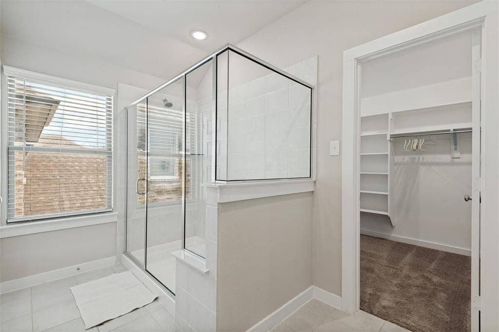 2808 Spring Side Drive, Royse City, TX 75189 Walk-in shower with a glass enclosure, tile surround, recessed lighting, and a walk-in closet featuring built-in shelving