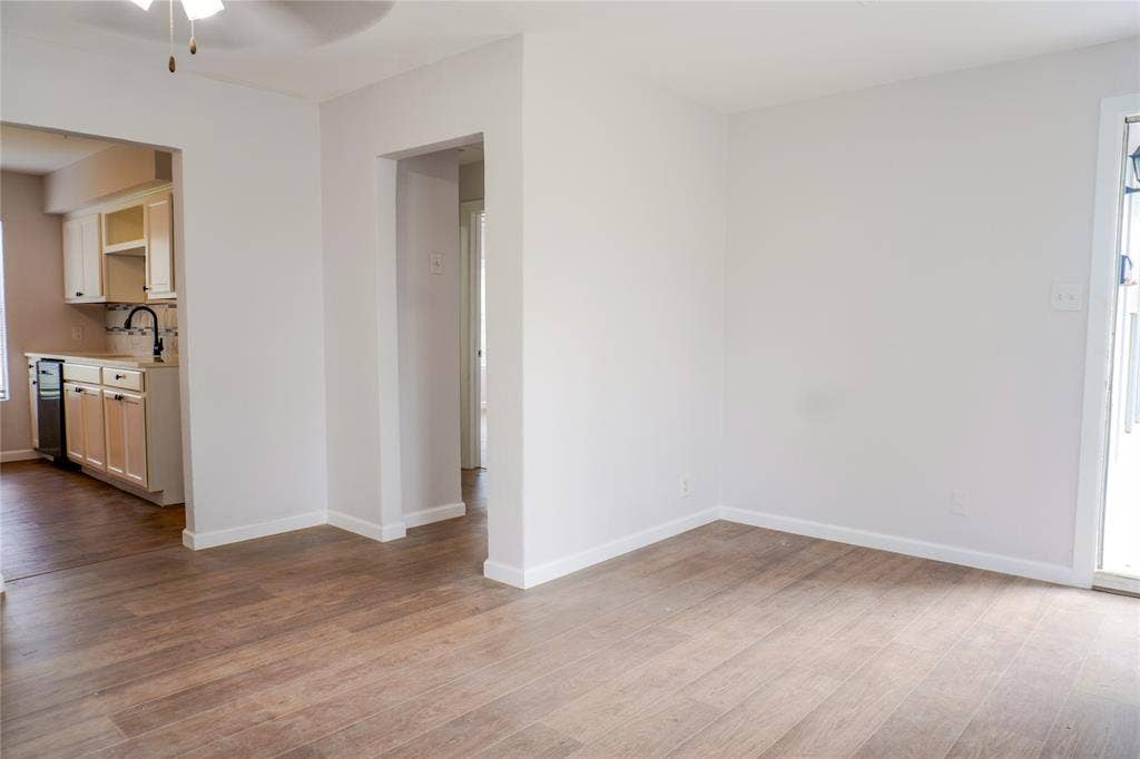 3229 Hardeman Street, Fort Worth, TX 76119 Neutral-toned interior featuring wood-finish flooring, white cabinetry, a tiled backsplash, and an integrated ceiling light fixture
