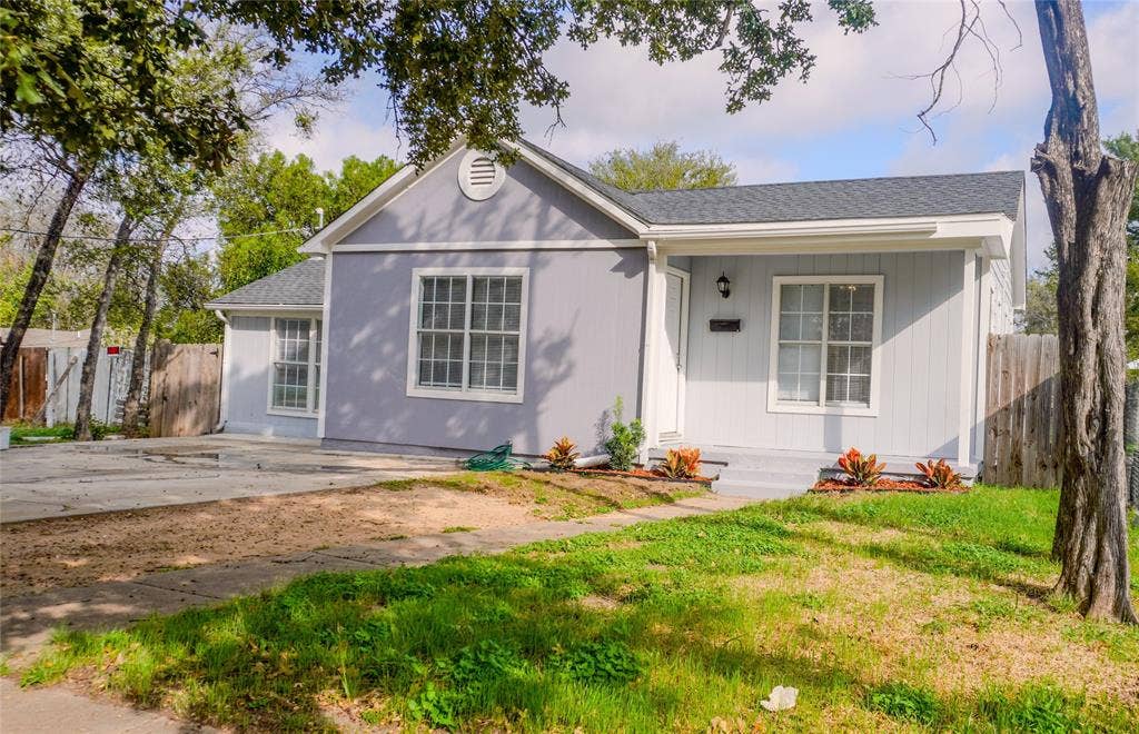 3229 Hardeman Street, Fort Worth, TX 76119 Single-story residence featuring light grey board-and-batten siding, a gable roofline, asphalt shingles, and a concrete driveway