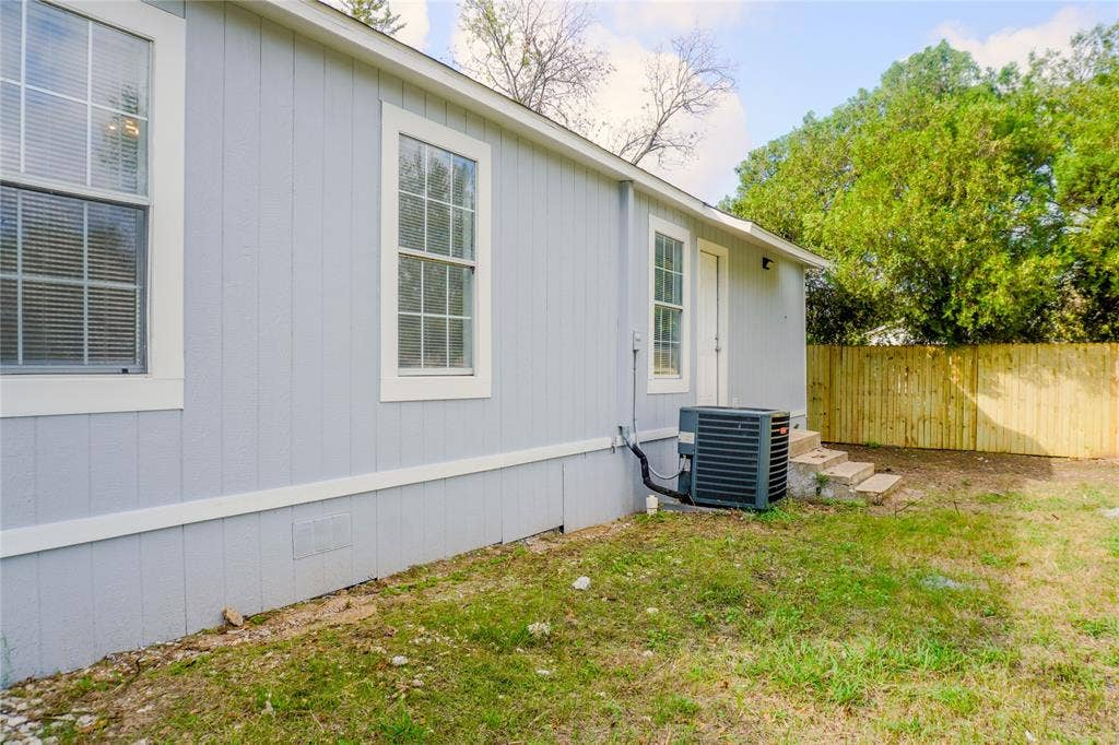 3229 Hardeman Street, Fort Worth, TX 76119 Exterior featuring vertical siding, grid-patterned windows, concrete steps, and a perimeter wood-slat fence