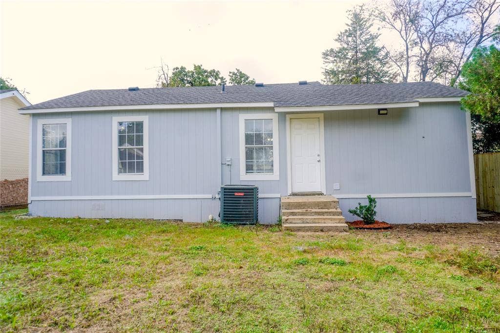 3229 Hardeman Street, Fort Worth, TX 76119 Single-story exterior featuring light-colored vertical siding, shingled roofing, three multi-pane windows, and concrete front steps