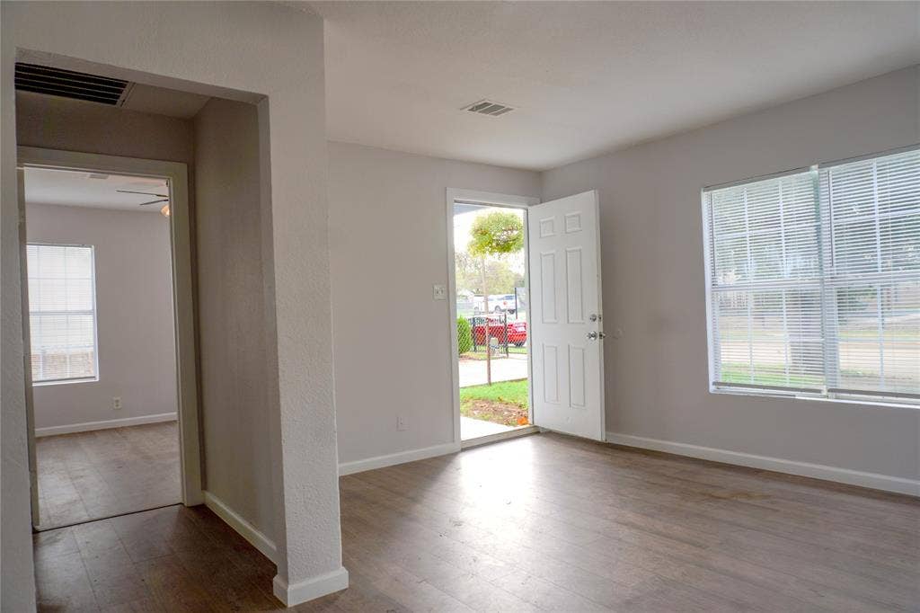 3229 Hardeman Street, Fort Worth, TX 76119 Neutral-toned interior featuring wood-finish flooring, multi-pane windows with blinds, and a six-panel exterior entry door