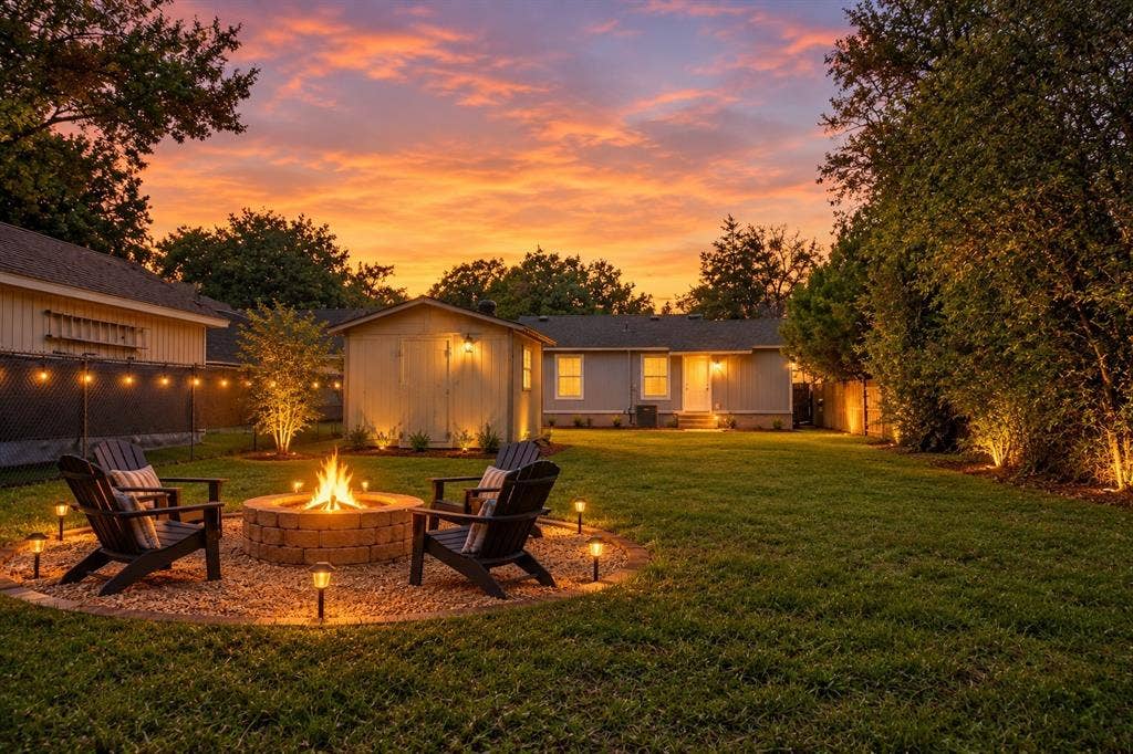 3229 Hardeman Street, Fort Worth, TX 76119 Expansive backyard featuring a circular stone fire pit, gravel ground cover, detached storage structure, perimeter landscape lighting, and a lawn