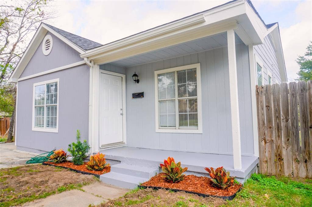 3229 Hardeman Street, Fort Worth, TX 76119 Exterior featuring vertical siding, a covered front porch, multi-pane windows, and a wood-paneled privacy fence