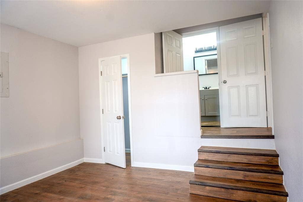 3229 Hardeman Street, Fort Worth, TX 76119 Wood-finish flooring, staircase with stained wood treads, two interior paneled doors, and built-in closet access