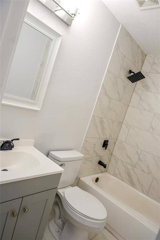 3229 Hardeman Street, Fort Worth, TX 76119 Grey vanity with a white countertop and basin, integrated matte black fixtures, and a shower-tub combination featuring tiled walls with a stone-finish pattern