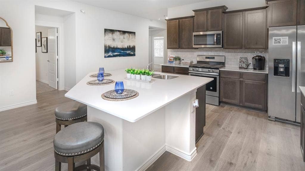 406 Campfield Drive, Caddo Mills, TX 75135 Modern kitchen featuring an angled island with a solid surface countertop and undermount sink