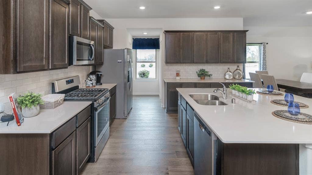 406 Campfield Drive, Caddo Mills, TX 75135 Modern kitchen featuring dark wood-finish cabinetry, light countertops, wood-finish flooring, a stainless steel gas range, and a stainless steel refrigerator