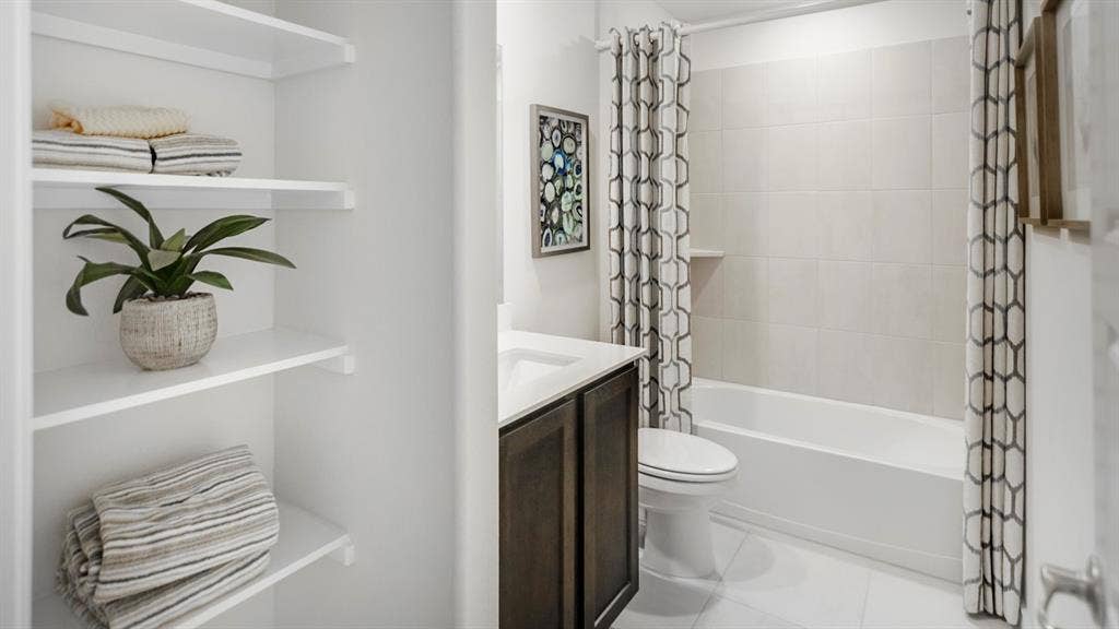 406 Campfield Drive, Caddo Mills, TX 75135 Full bathroom featuring a dark wood-finish vanity with an integrated sink, a white bathtub with subway tile surround, and a built-in shower niche