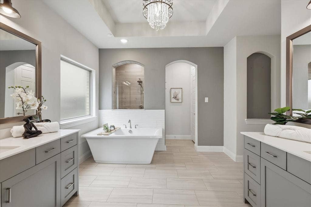 A spa-like primary bathroom offering dual vanities, a freestanding soaking tub, a spacious walk-in shower, and a massive closet with direct, convenient access to the laundry room.