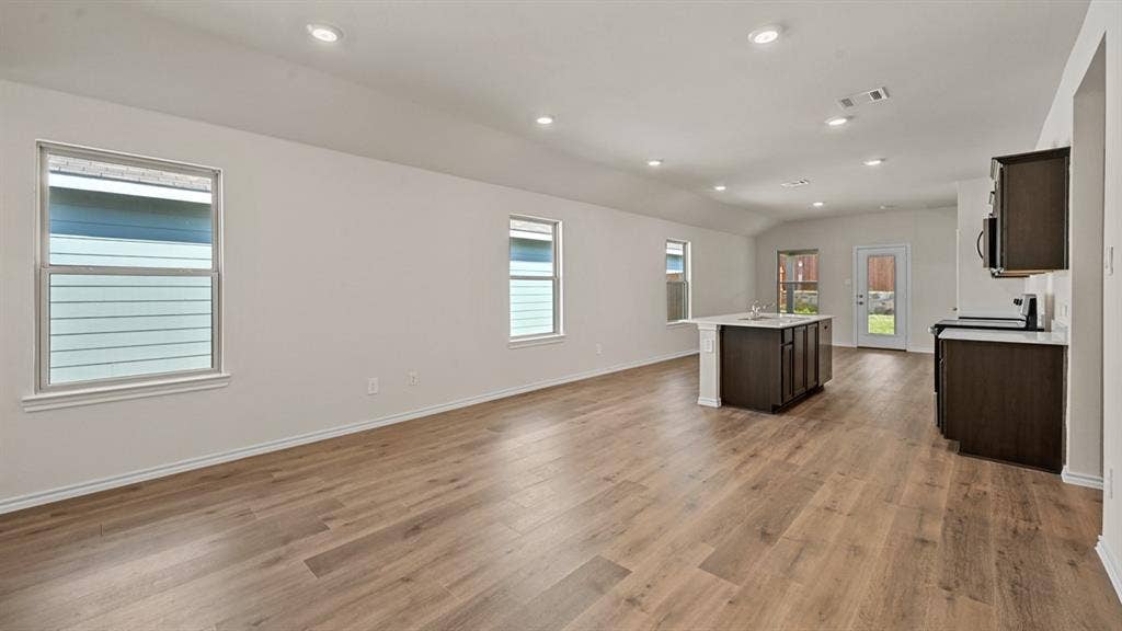 Open-concept living area featuring wood-finish flooring, recessed lighting, and ample natural light from multiple windows