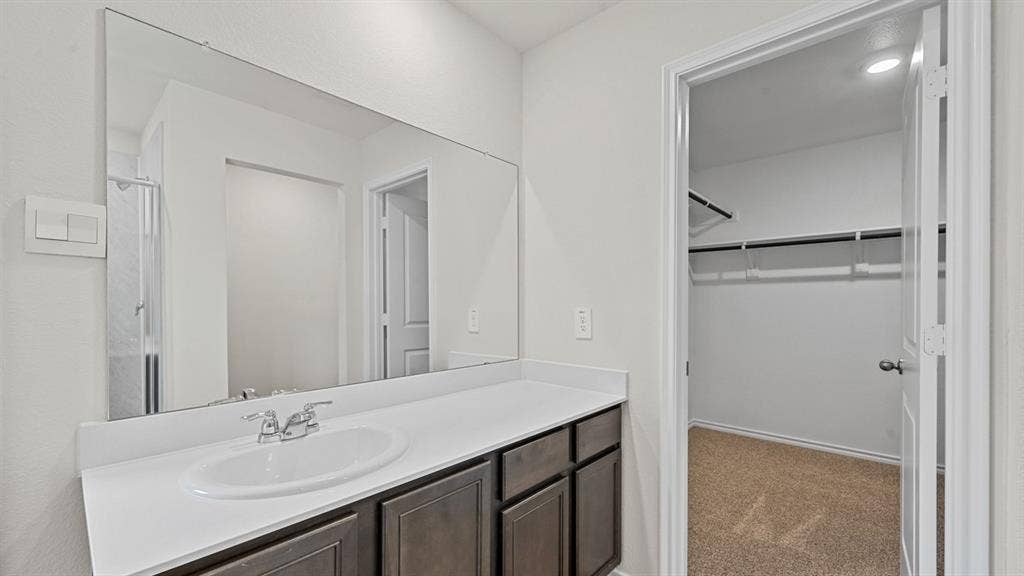 Vanity with an integrated sink, polished chrome faucet, and expansive wall-mounted mirror