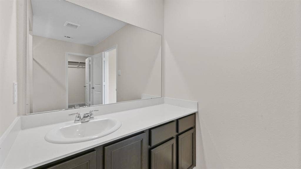 5827 Blue Sky Drive, Crandall, TX 75114 Bathroom vanity featuring a single basin sink, chrome faucet, and expansive wall-mounted mirror