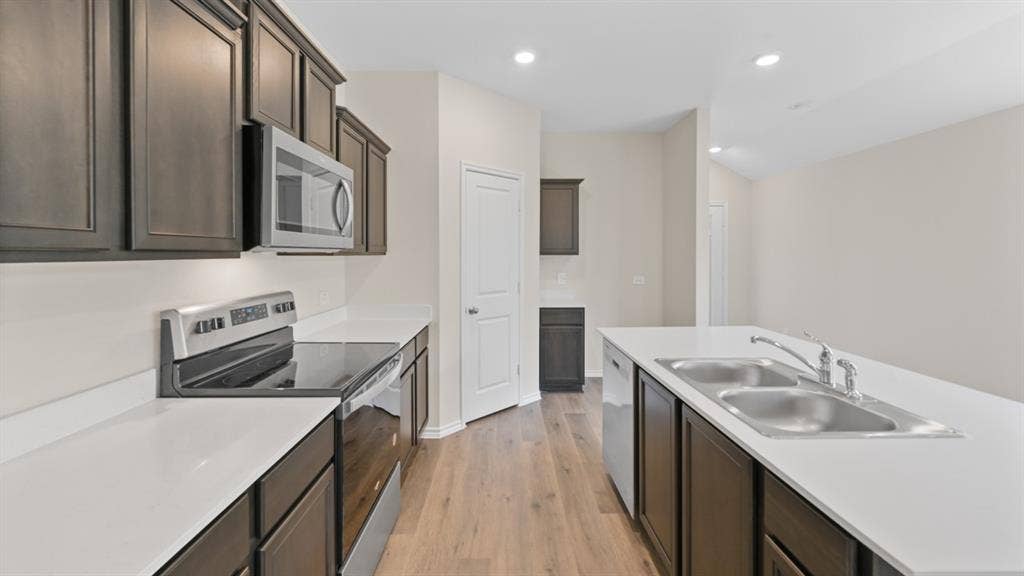 5827 Blue Sky Drive, Crandall, TX 75114 Modern kitchen featuring dark wood cabinetry, light countertops, stainless steel appliances, and wood-finish flooring