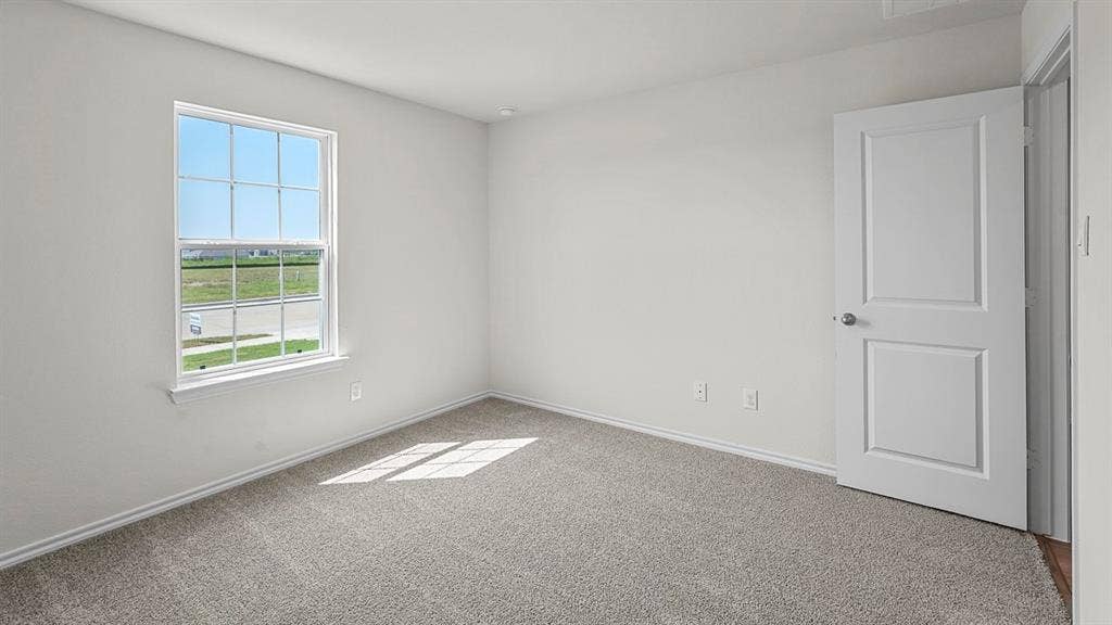 Neutral-toned room featuring wall-to-wall carpeting, a single-hung window with a grid pattern, and a two-panel interior door