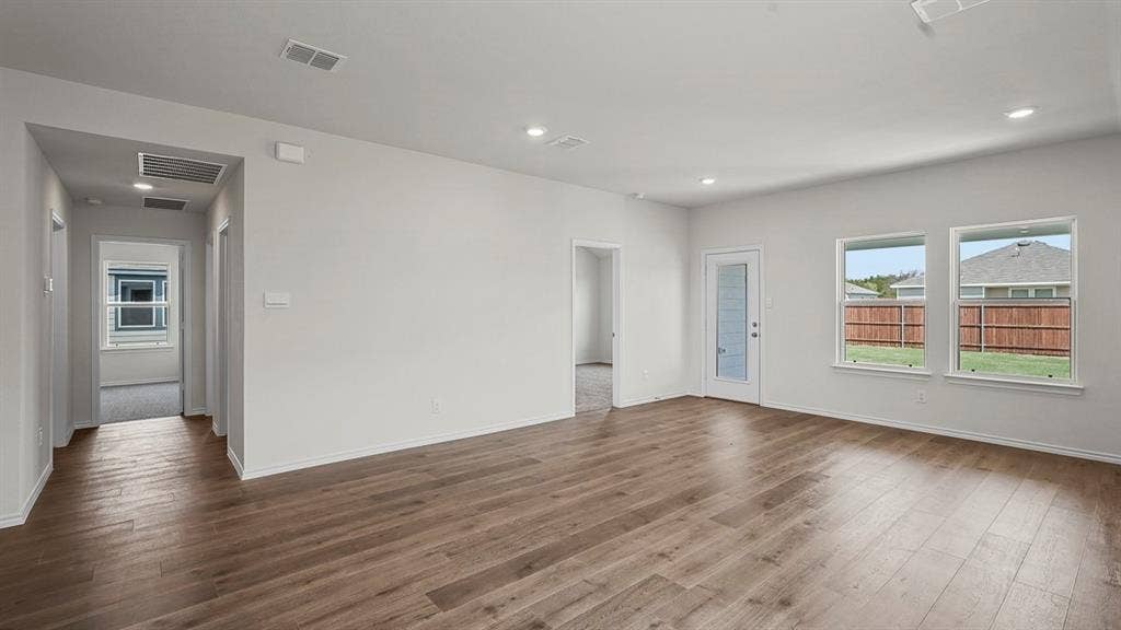 Open-concept interior featuring wood-finish flooring, recessed lighting, and multiple windows providing natural light, inclusive of a glass-paneled exterior door