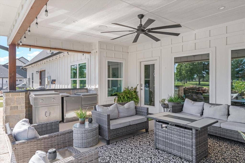 203 Splitrail Drive, Mabank, TX 75143 Covered patio featuring board and batten siding, a stone-base outdoor kitchen with built-in stainless steel appliances, recessed ceiling lighting, and a multi-blade ceiling fan