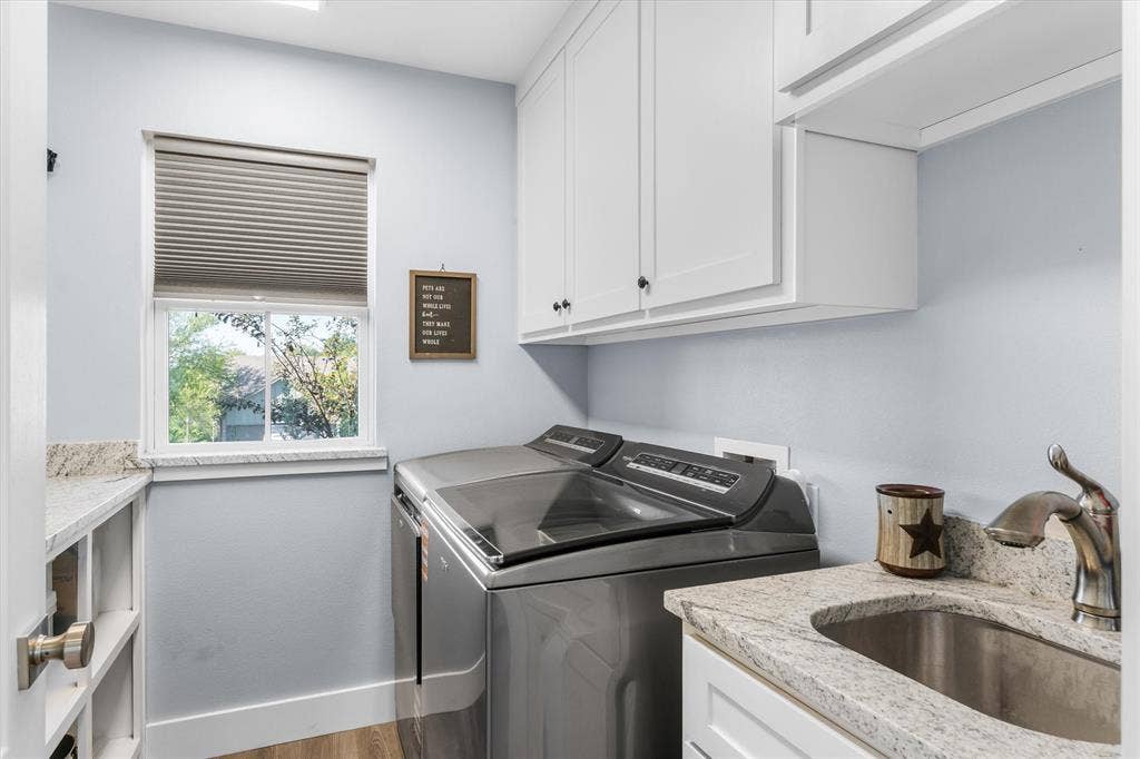 203 Splitrail Drive, Mabank, TX 75143 Laundry area featuring light-toned stone countertops, white shaker-style cabinetry, an integrated stainless steel basin with a gooseneck faucet, and wood-finish flooring