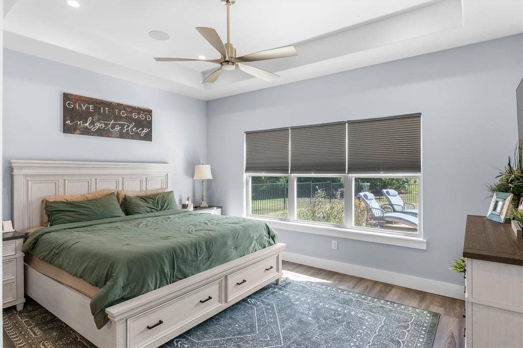 203 Splitrail Drive, Mabank, TX 75143 Tray ceiling featuring recessed lighting and a central ceiling fan, expansive triple-pane window, and wood-finish flooring