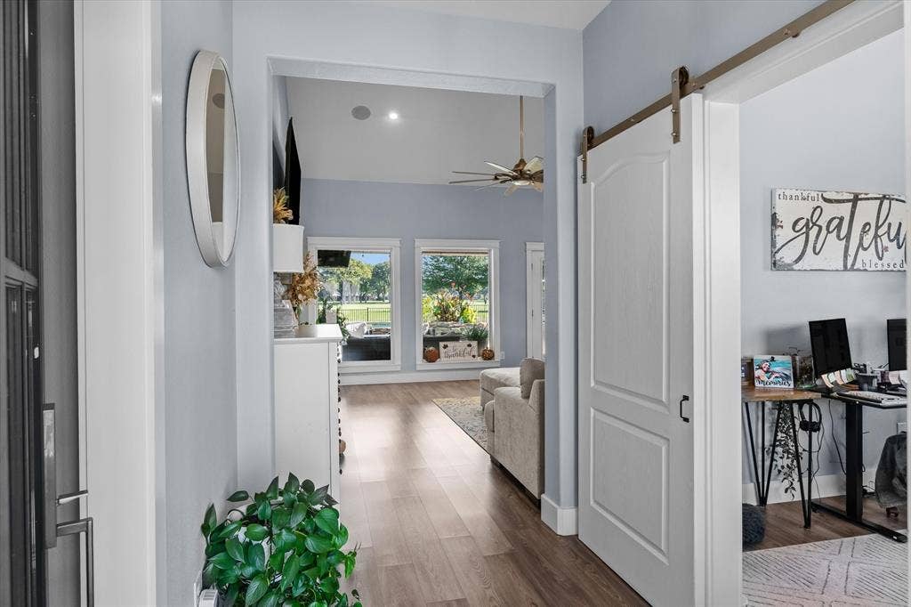 203 Splitrail Drive, Mabank, TX 75143 Entryway featuring wood-finish flooring, white paneled interior door, and a sliding barn-style door with metal track hardware