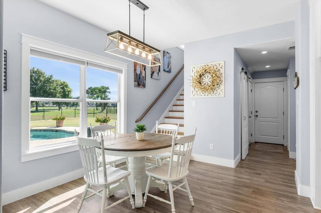 203 Splitrail Drive, Mabank, TX 75143 Wood-finish flooring, rectangular multi-light pendant fixture, staircase with wood handrail, and large window with exterior pool visibility