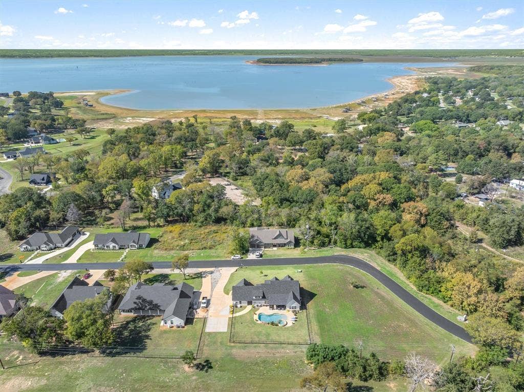 203 Splitrail Drive, Mabank, TX 75143 Aerial perspective of property featuring an inground swimming pool, asphalt driveway, manicured lawn, and perimeter fencing