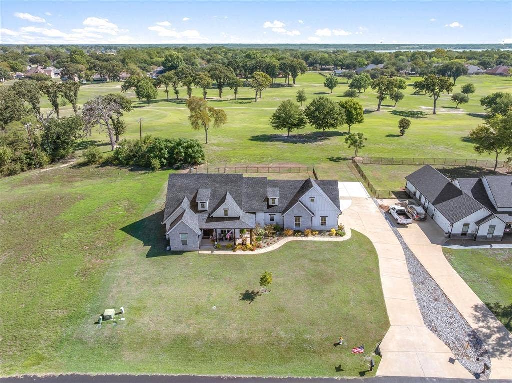 203 Splitrail Drive, Mabank, TX 75143 Multi-structure property featuring a gabled roofline, concrete driveway, stone and vertical siding exterior, and expansive acreage