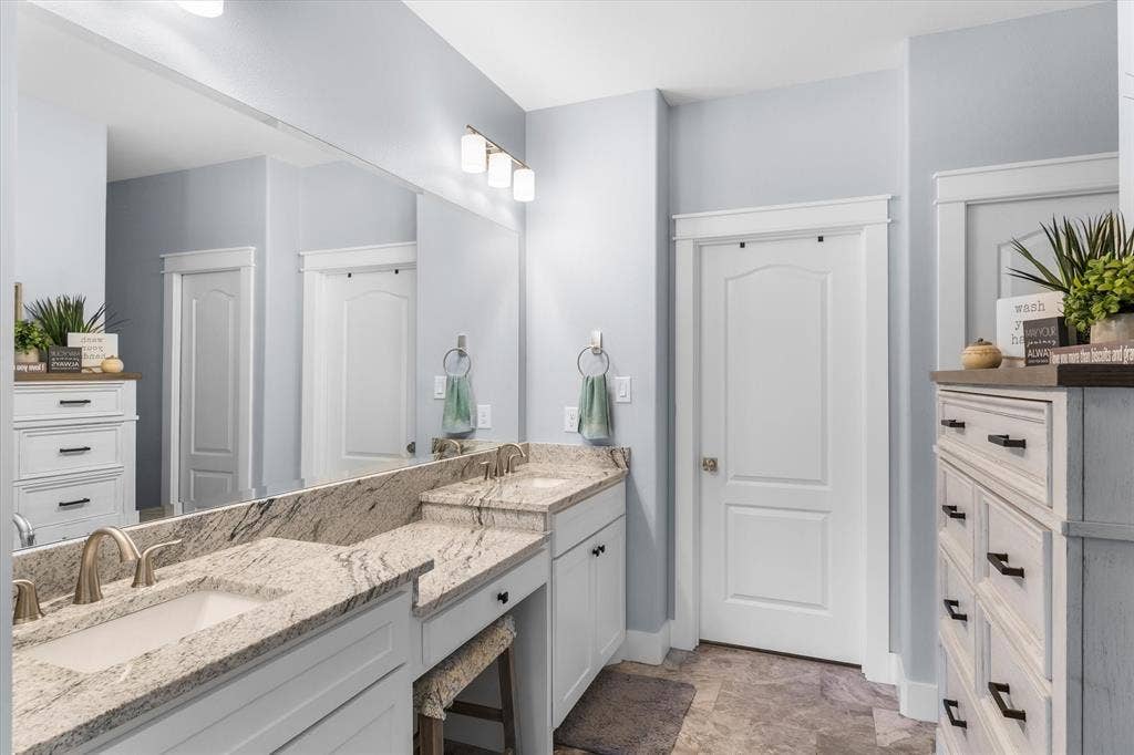 203 Splitrail Drive, Mabank, TX 75143 Dual-sink vanity with stone countertop, undermount basins, expansive wall-to-wall mirror, and neutral-toned tile flooring