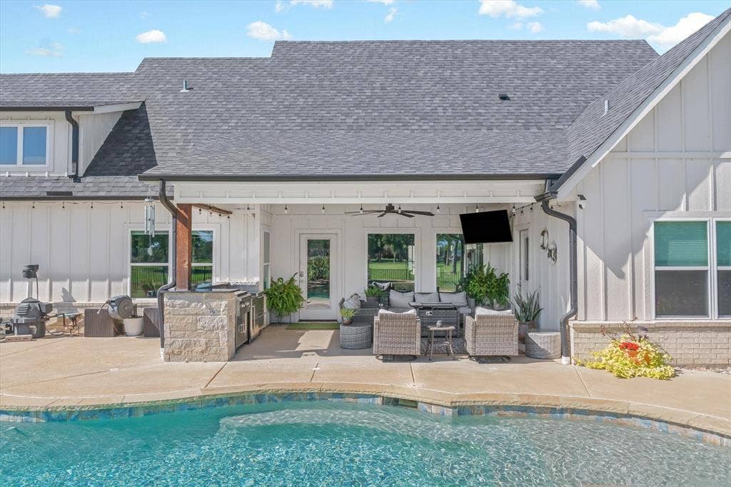 203 Splitrail Drive, Mabank, TX 75143 Covered outdoor living area featuring a stone-clad built-in kitchen, ceiling fan, hardscaped patio, and an in-ground swimming pool