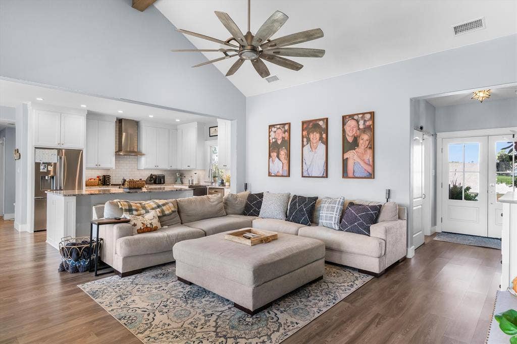 203 Splitrail Drive, Mabank, TX 75143 Vaulted ceiling featuring an expansive multi-blade ceiling fan, wood-finish flooring, and white cabinetry with stainless steel appliances