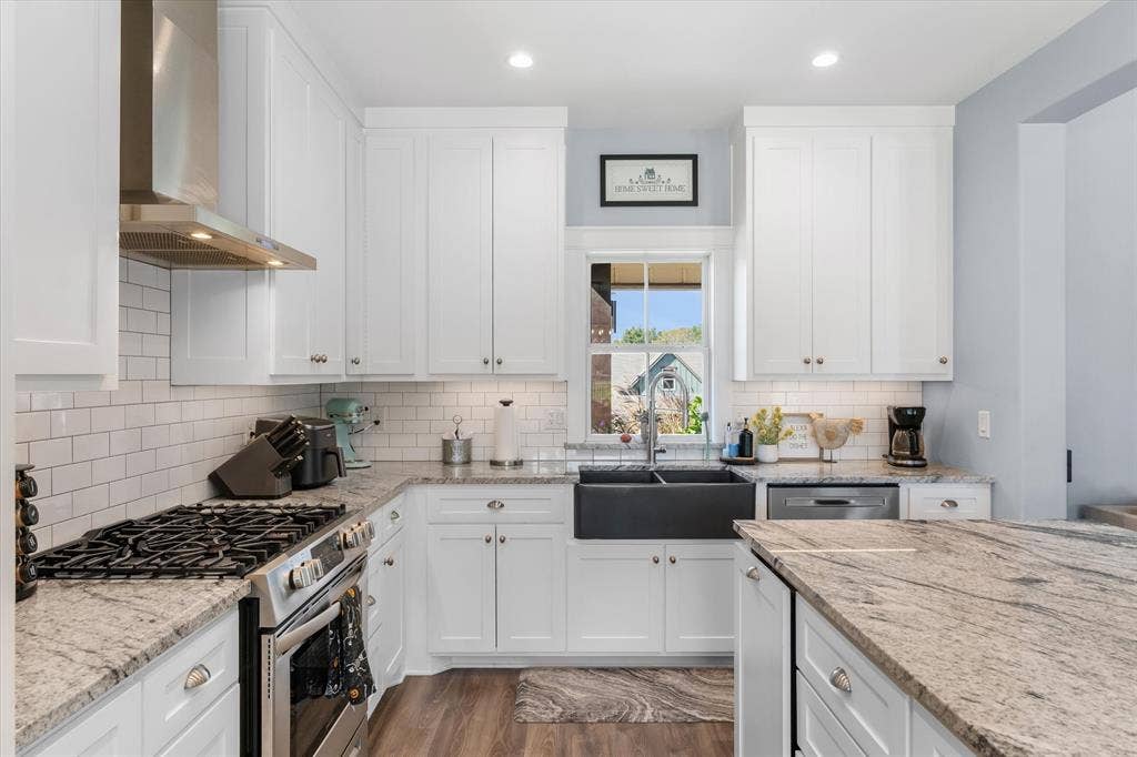203 Splitrail Drive, Mabank, TX 75143 Kitchen featuring white shaker-style cabinetry, stone countertops, farmhouse-style sink, stainless steel chimney range hood, and subway tile backsplash
